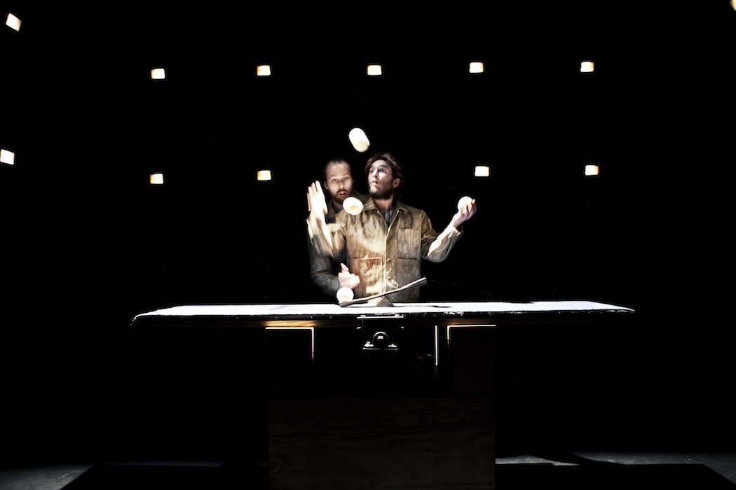 Two performers juggle props, with one standing behind the other.