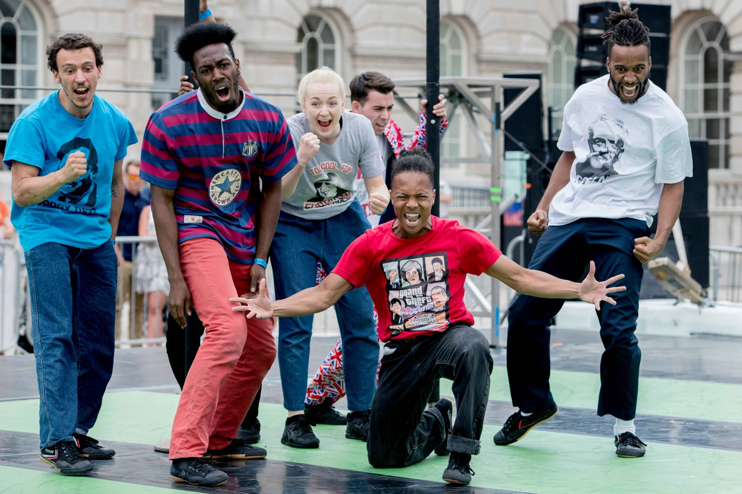 Group of dancers performing on stage with one person in the foreground in a dynamic pose.