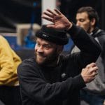 six performers in an indoor rehearsal space are pulling small white balls amongst each other