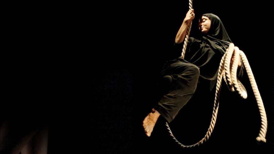 A performer in head to toe black costume swings gracefully on a rope against a dark backdrop, creating a dramatic and mysterious atmosphere What If…? | Layla Rosa ©